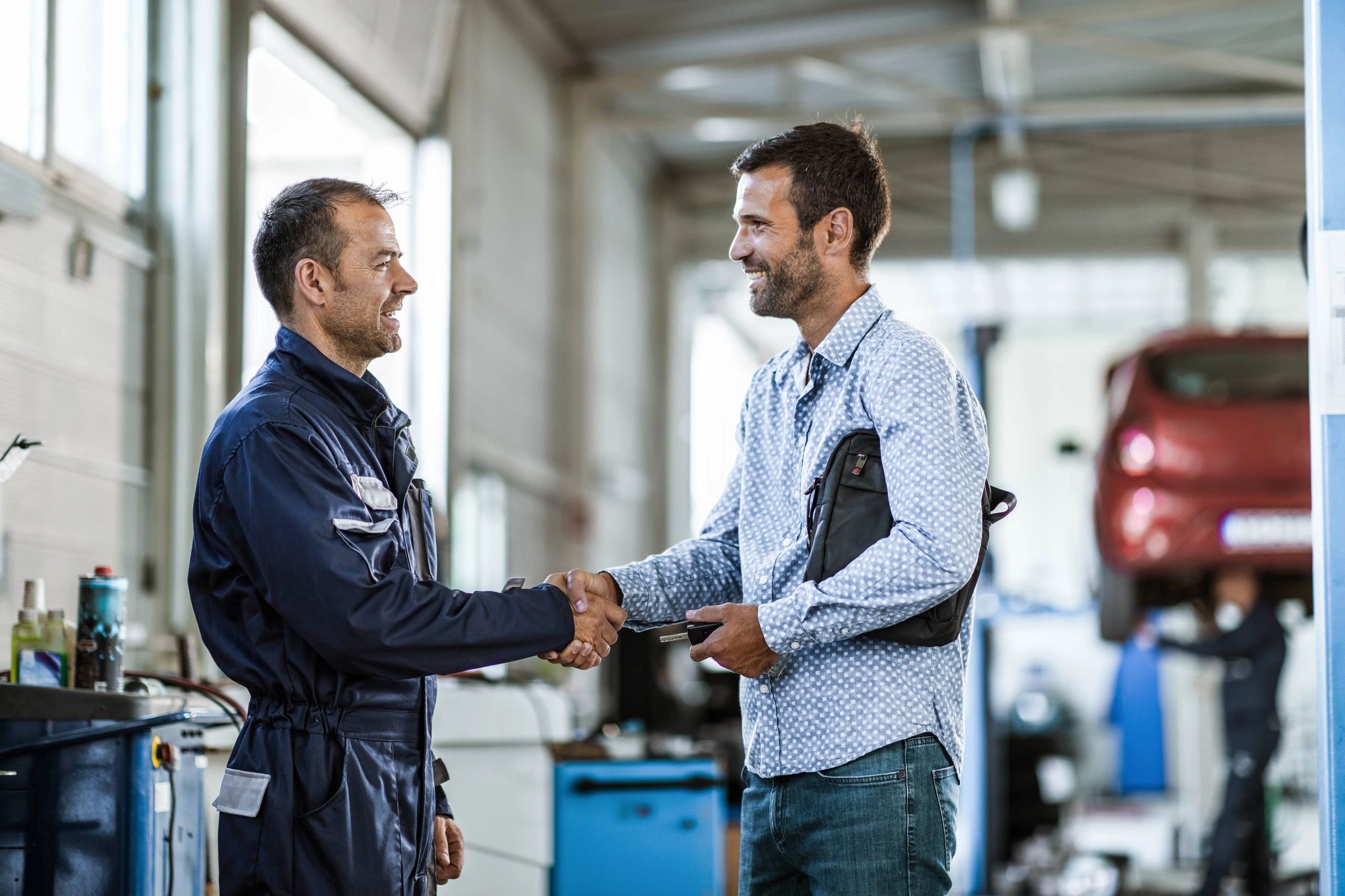Happy customer shaking hands with a mechanic in an auto repair shop