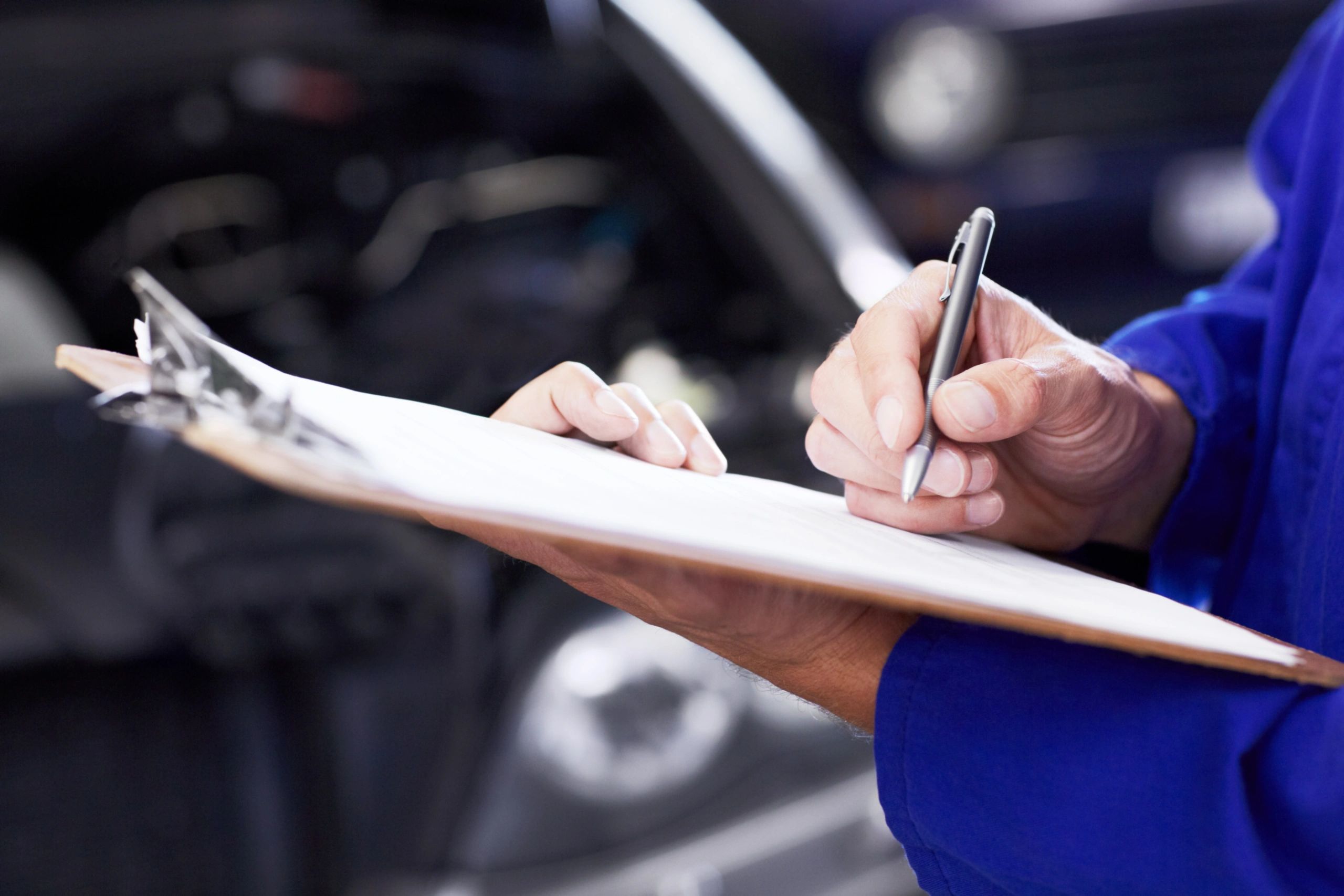 Mechanic completing a vehicle inspection checklist on a clipboard