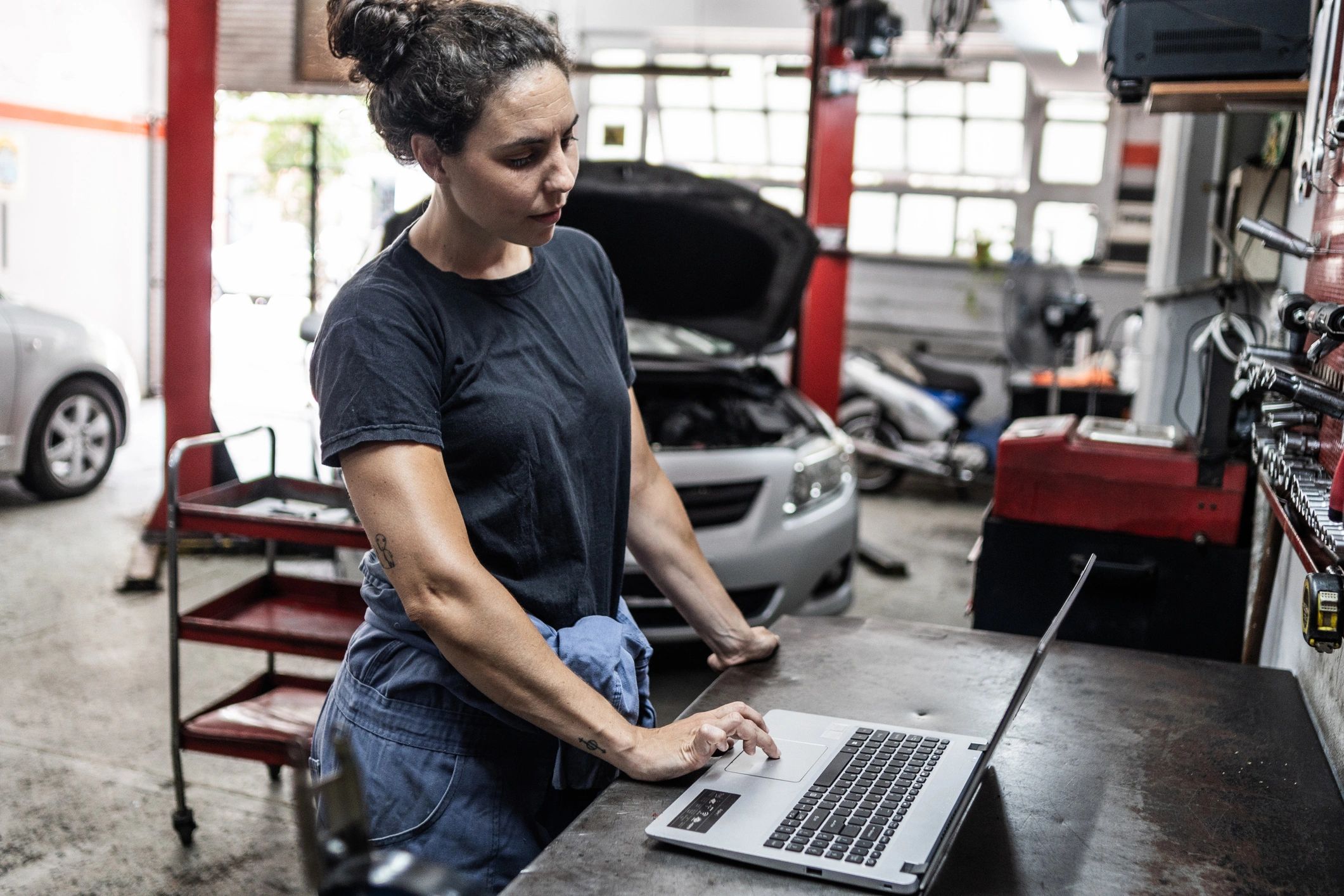 Technician using a laptop for vehicle diagnostics in an auto repair shop
