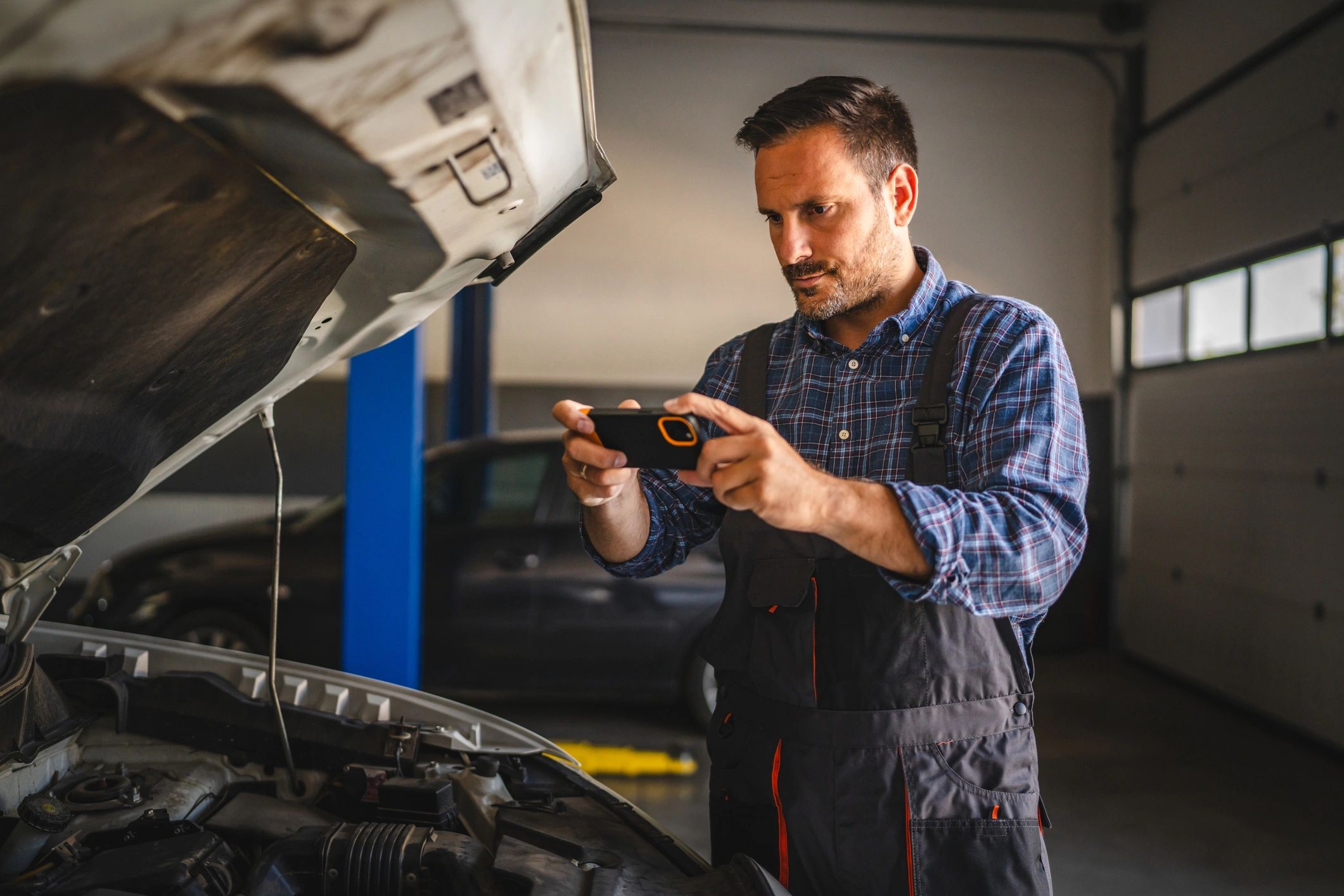 Mechanic documenting an engine bay during a diagnostic inspection