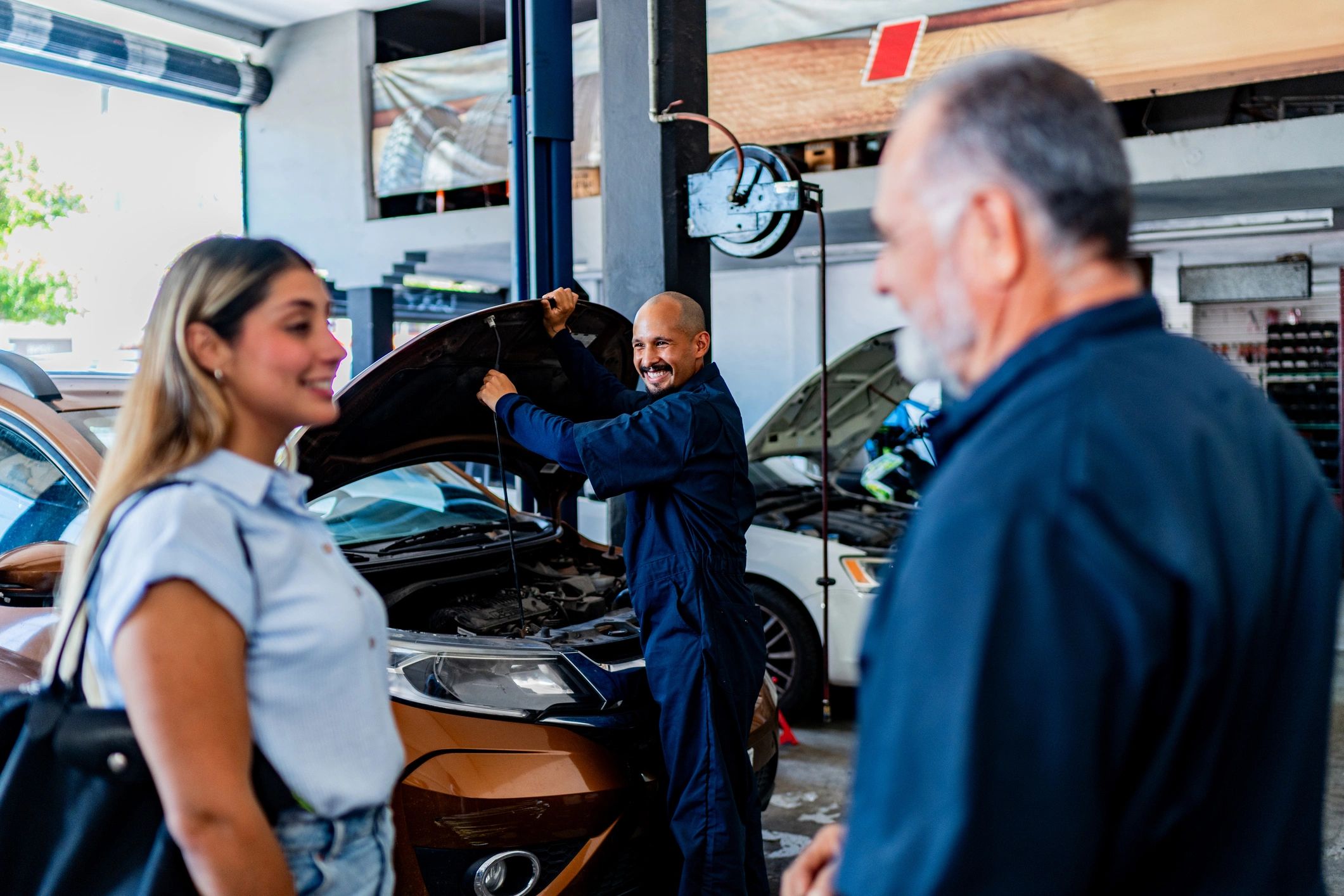Mechanic showing an open hood to a customer at an auto repair shop