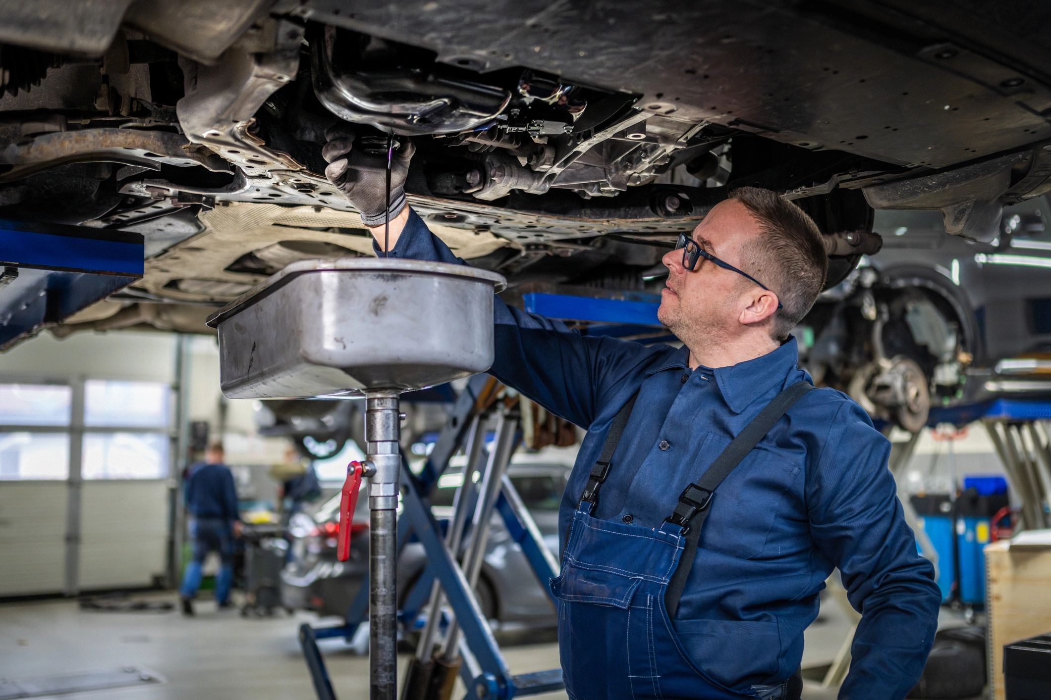 Technician performing fluid service under a vehicle