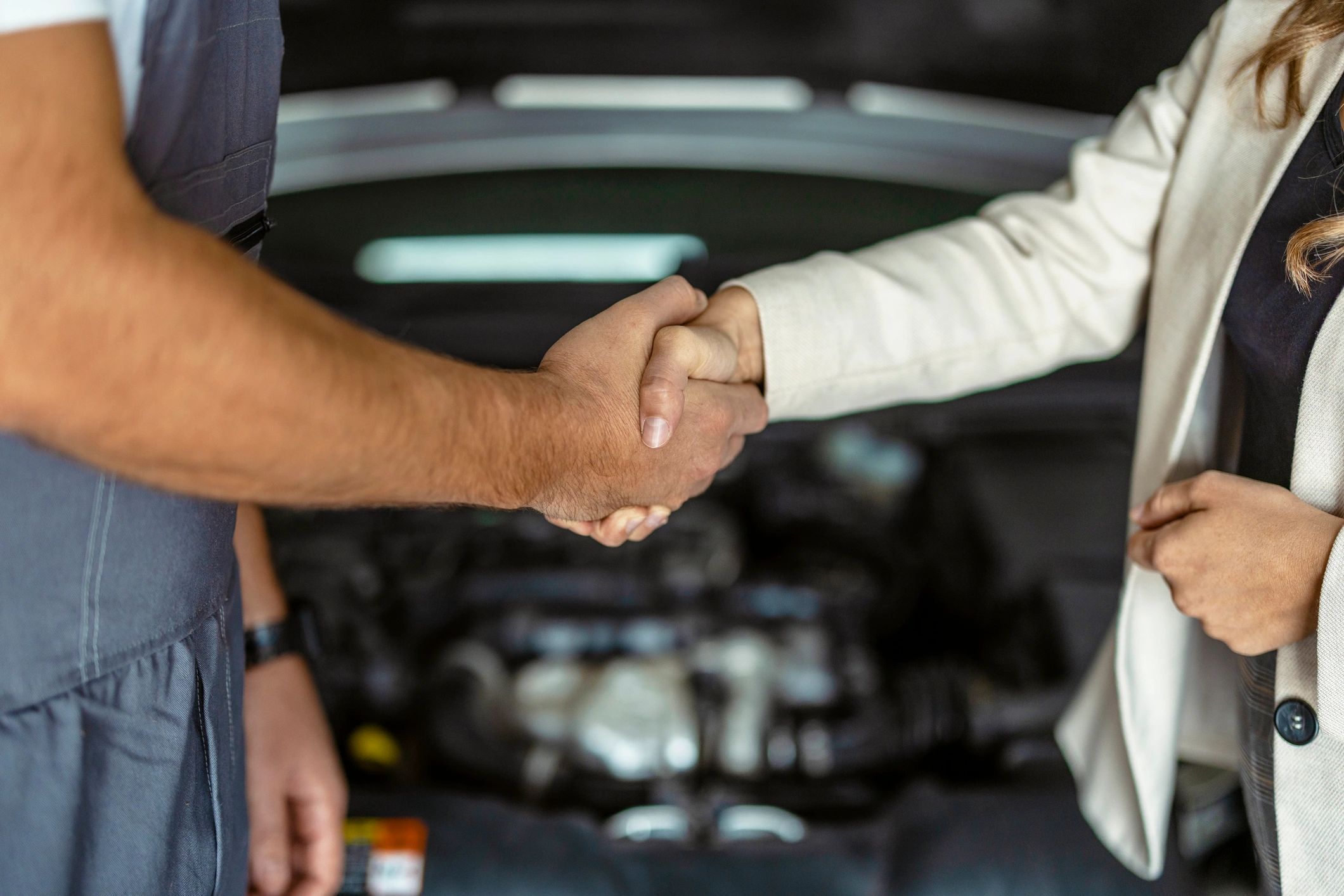Close-up handshake between mechanic and client in an auto repair service